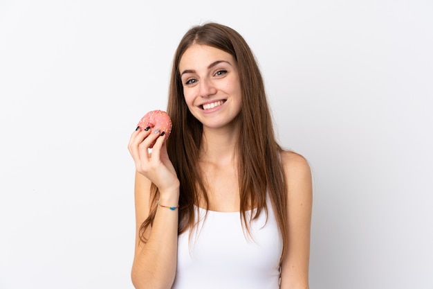 Giovane donna sopra la parete bianca isolata che tiene una ciambella e felice