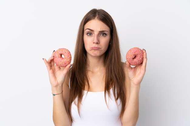 슬픈 표정으로 도넛을 들고 격리 된 흰 벽에 젊은 여자