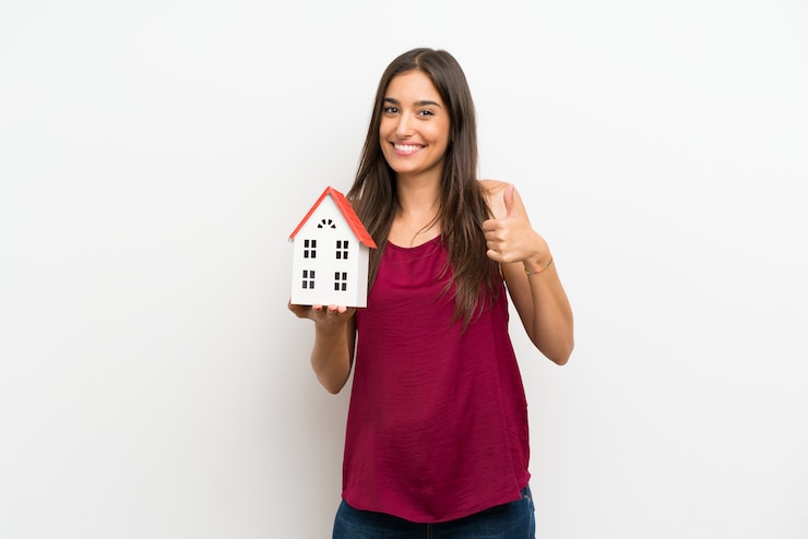 फोटो young woman over isolated white wall holding a little house