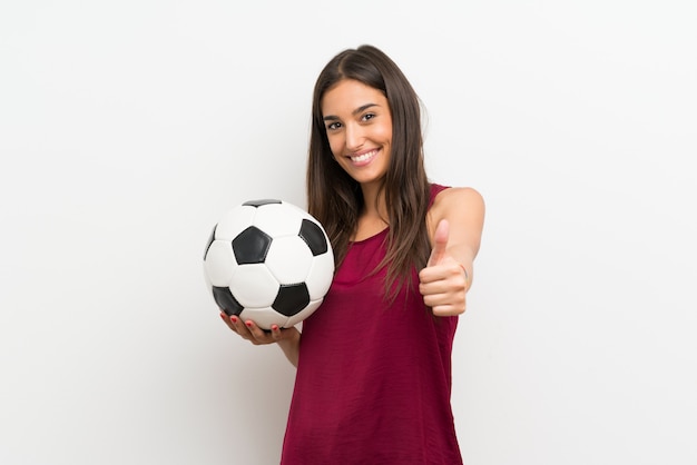 Young woman over isolated white wall holding a soccer ball