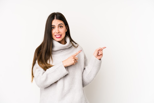 Young woman isolated on a white wall shocked pointing with index fingers to a copy space