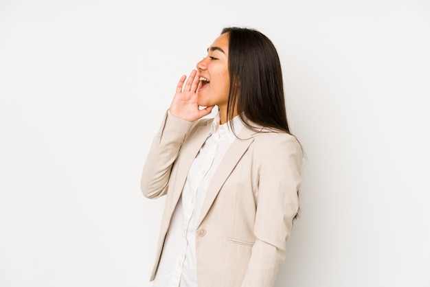 Young woman isolated on a white wall shouting and holding palm near opened mouth.