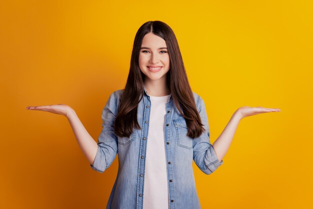 Young woman isolated yellow background holding copyspace advertise