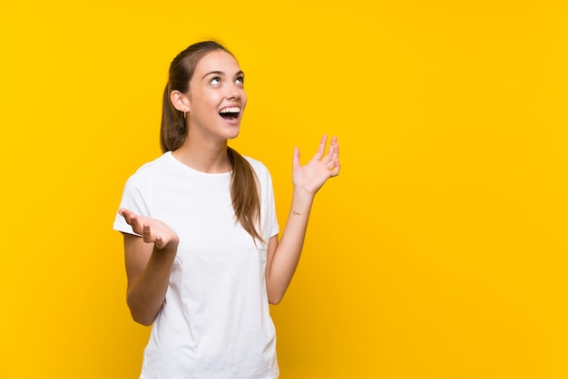 Young woman over isolated yellow background with surprise facial expression