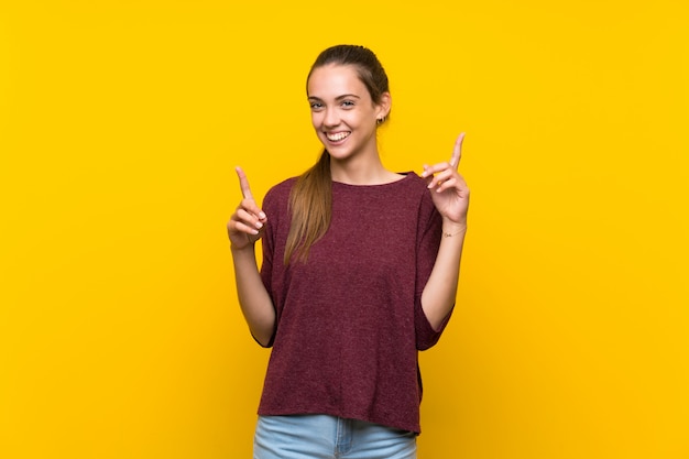 Young woman isolated on yellow  pointing up a great idea