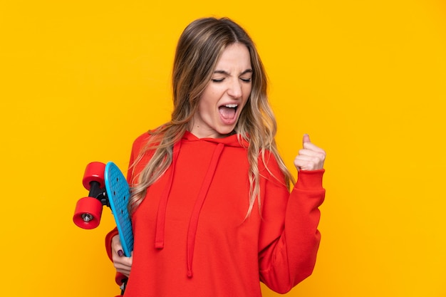 Young woman over isolated yellow wall with a skate