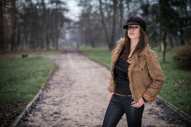 young woman in jacket standing and posing at the forest