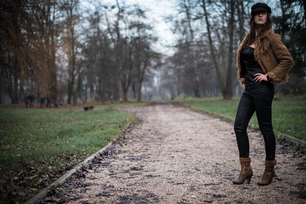 young woman in jacket standing and posing at the forest