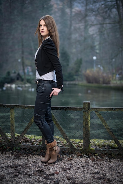 young woman in jacket standing and posing at the lake