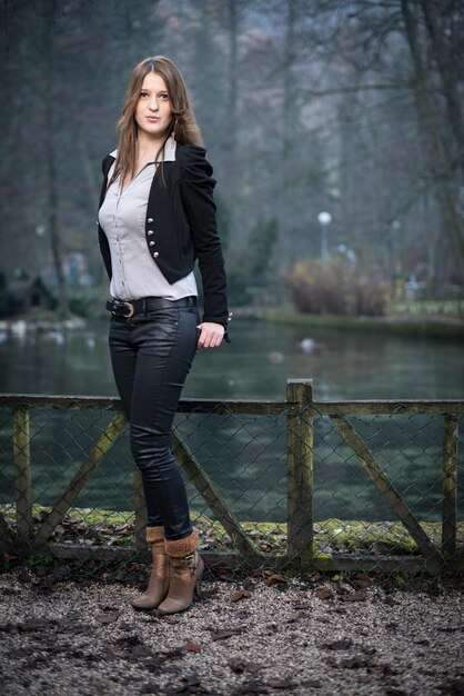 Young woman in jacket standing and posing at the lake