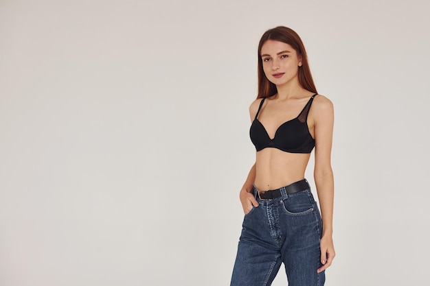 Young woman in jeans and bra indoors White background