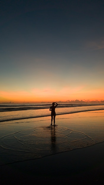 Foto giovane donna che pareggia sulla spiaggia al tramonto bellissimo