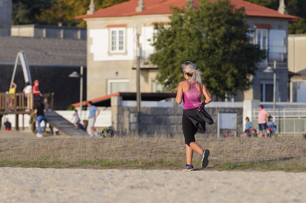 街のビーチ、夕日の照明でジョギング若い女性