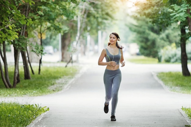 緑の公園で小道をジョギングしている若い女性