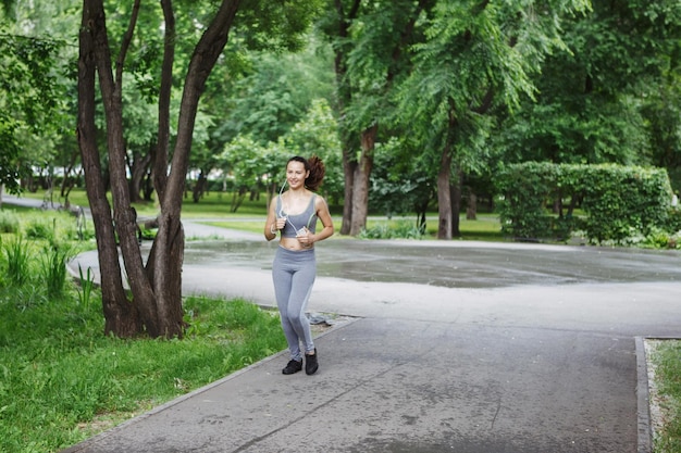 Young woman jogging down a path in a green park