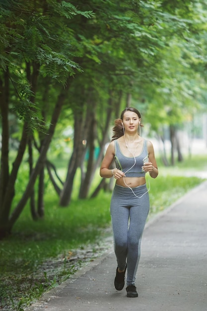 Young woman jogging down a path in a green park