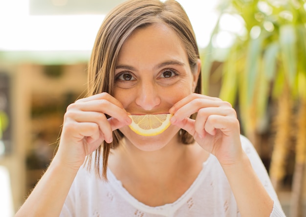 young woman joking with lemon slice in a restaurant