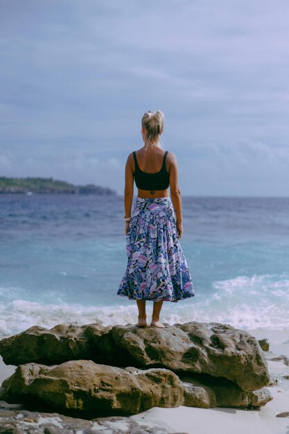 旅の若い女性。海沿いの岩の上の旅行者。