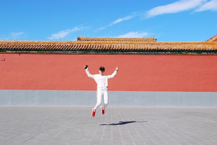 Photo young woman jumping against temple during sunny day