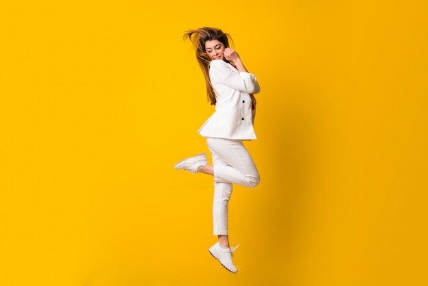 Young woman jumping over isolated yellow wall