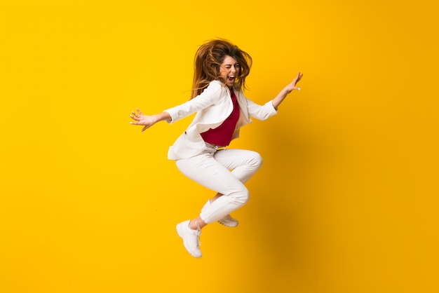 Young woman jumping over isolated yellow wall