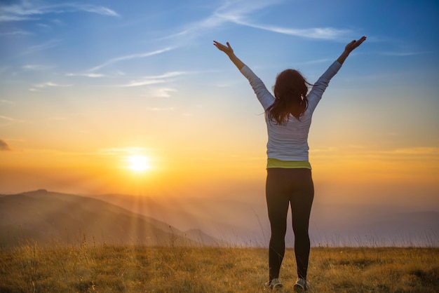 Young woman jumping at sunset mountains