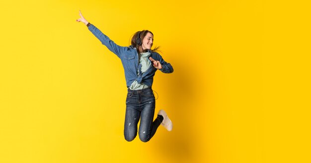 Young woman jumping over yellow 