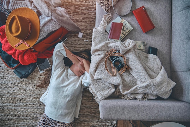 Young woman just arrived in the hotel and relaxing at the floor after a long flight