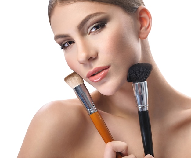 Young woman keeping makeup brushes looking at camera