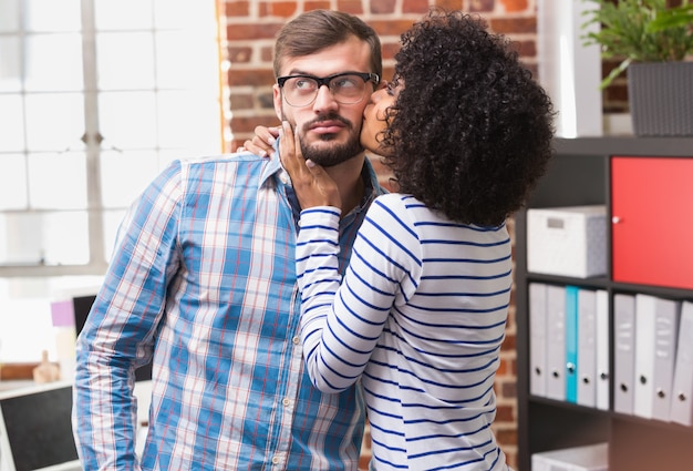 Photo young woman kissing man in office