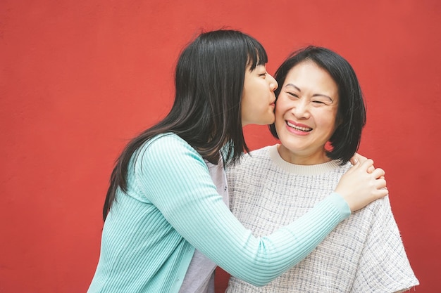 Photo young woman kissing mother while standing against red background