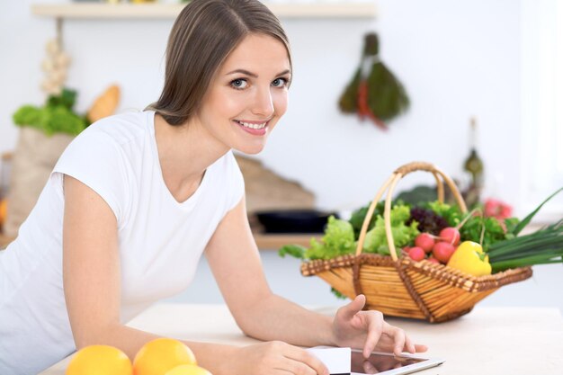 Young woman at the kitchen making online shopping by tablet computer and credit card