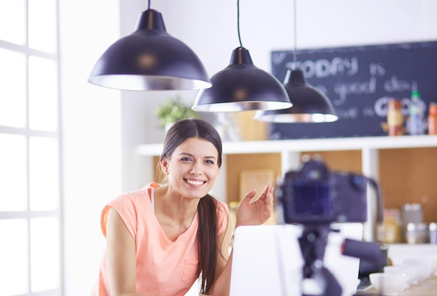 Young woman in kitchen with laptop computer looking recipes smiling Food blogger concept