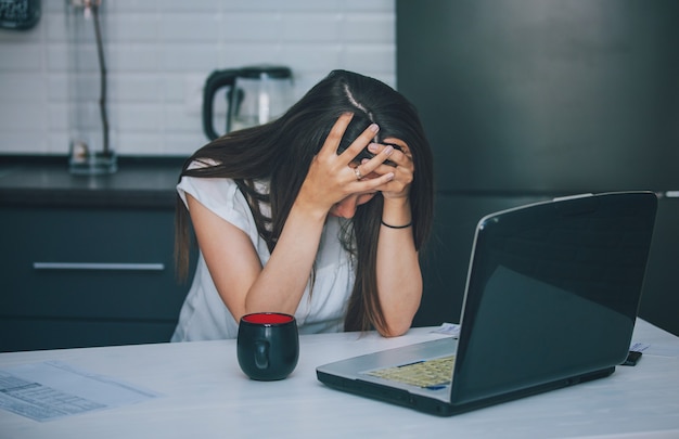 young woman in the kitchen working with laptop