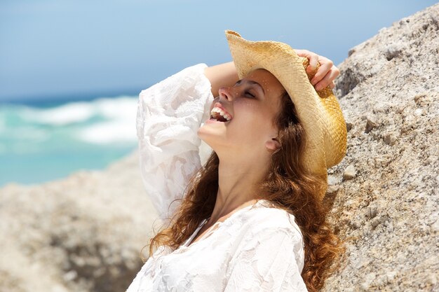 Young woman laughing with cowboy hat at the beach