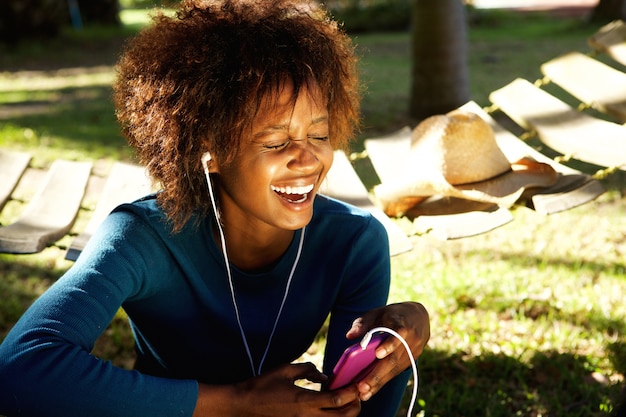Молодая женщина смеется с мобильного телефона и наушников