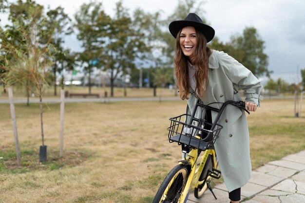 Photo a young woman laughs while sitting on a bicycle while walking around the city in a black hat and a