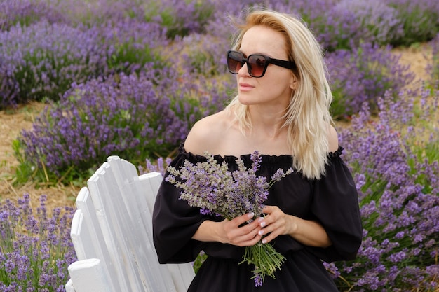 Young woman in a lavender field holding a bouquet of lavender a sunny day