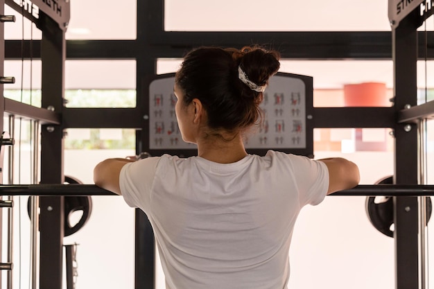 Giovane donna appoggiata su un bilanciere in palestra