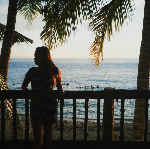 Photo young woman leaning on railing at beach