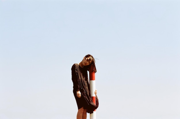 Photo young woman leaning on striped pole