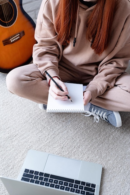 Young woman learning to play guitar at home