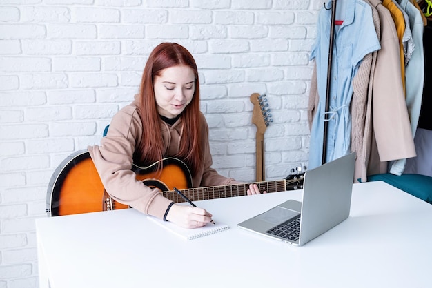 Young woman learning to play guitar at home