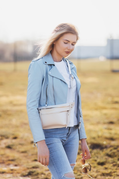 Young woman in a leather jacket and jeans posing outdoors