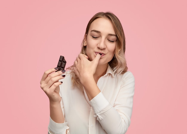 Young woman licking finger with chocolate