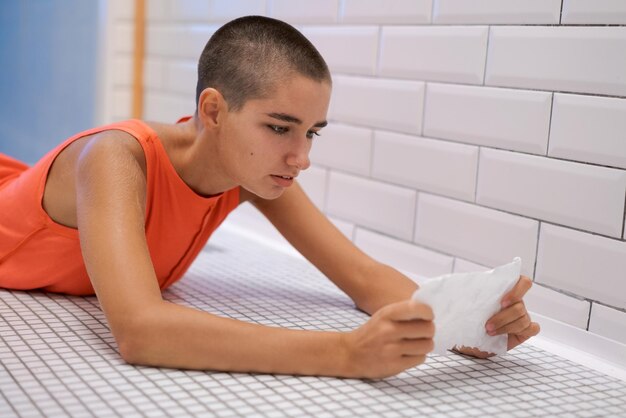 若い女性はタイルの上に横たわって不安で手紙を読む悪いニュースを受け取った女の子