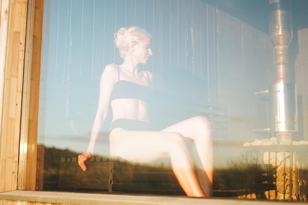 Young woman lies on wooden shelf in spa sauna treat yourself