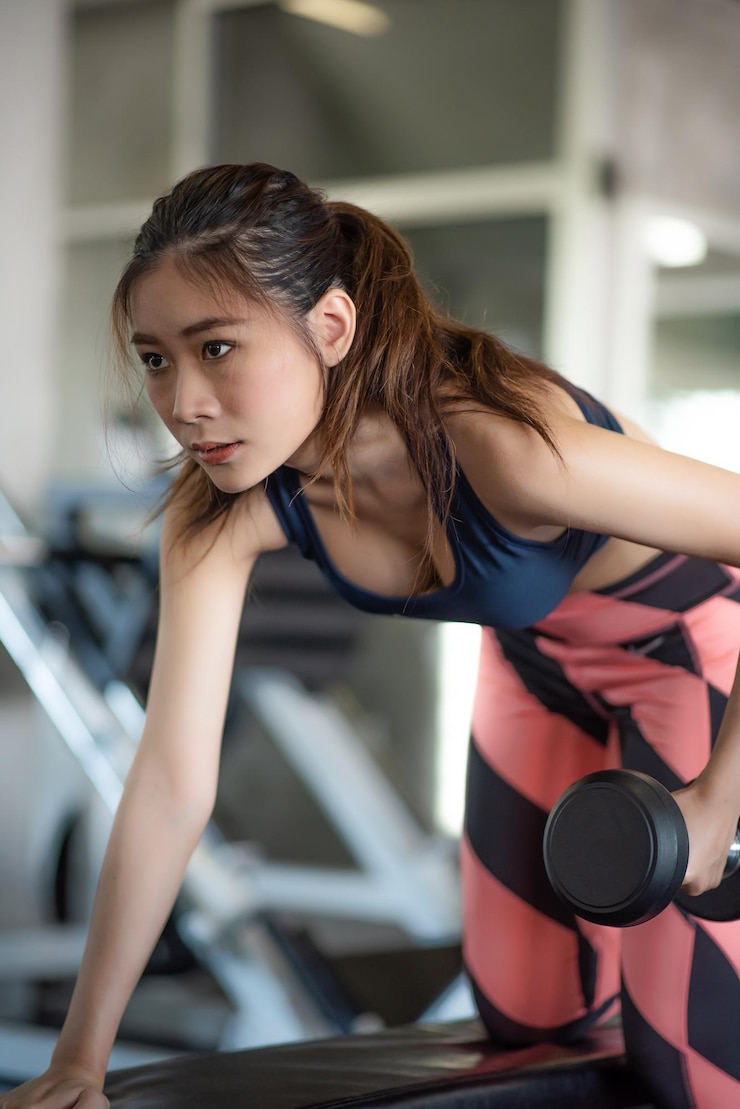 Photo ジムでダンベルを上げている若い女性