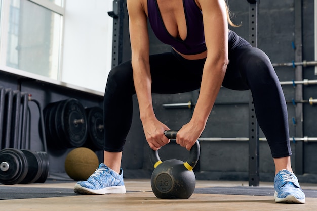 Photo young woman lifting kettlebell in squat