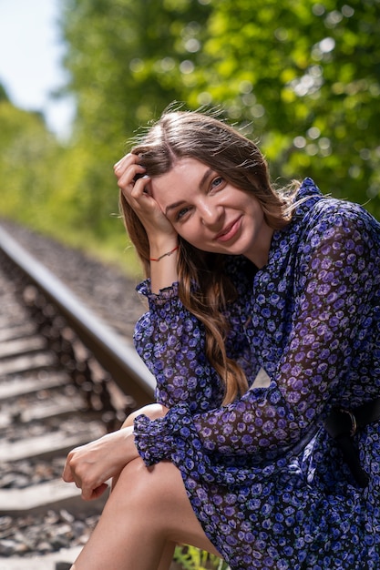 Young woman in a light blue dress sat down to rest on the rails